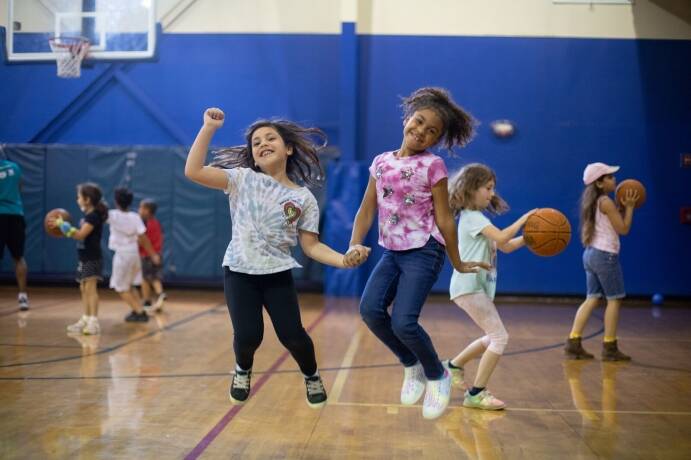 Girls holding hands jumping during Parents Night Out at the YMCA
